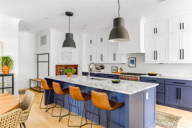 a kitchen with stainless steel appliances a sink a stove a dining table and chairs