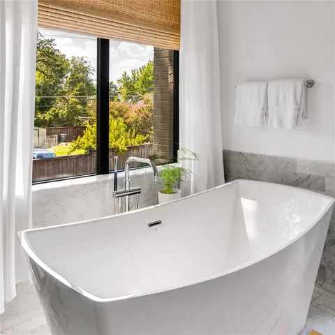 a white bath tub sitting in a bathroom next to a window