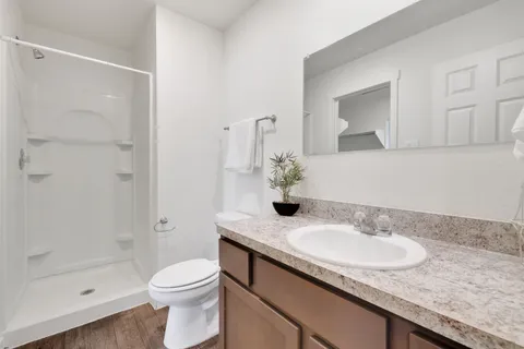 a bathroom with a granite countertop sink a toilet and shower