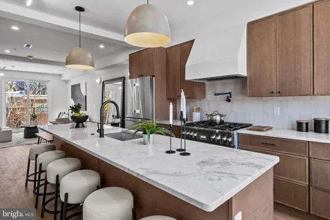 a kitchen with stainless steel appliances granite countertop a sink a stove and a wooden cabinets