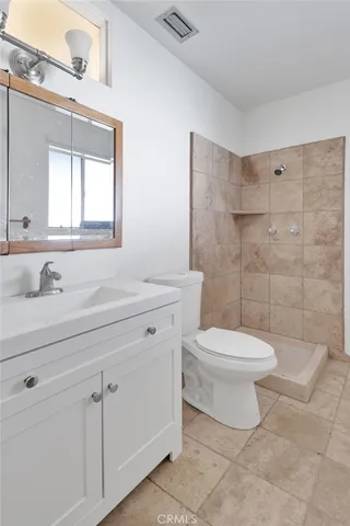 a bathroom with a toilet a sink a mirror and a shower