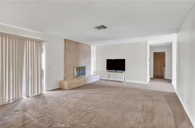 an empty room with windows and fireplace