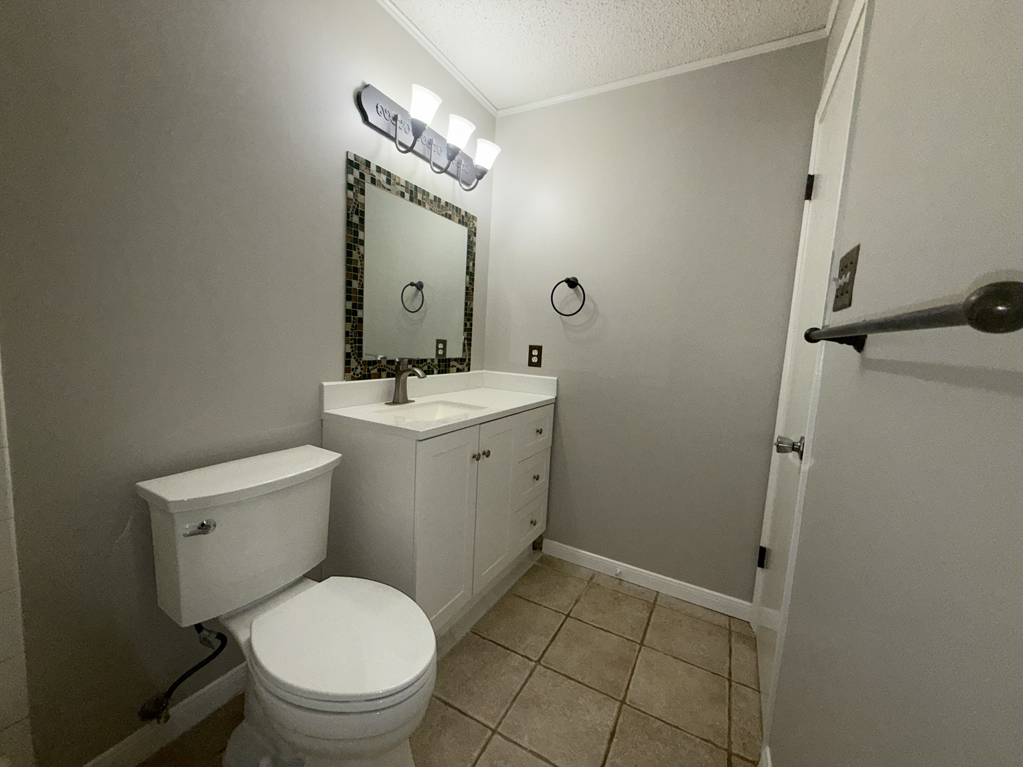 7806 Topawa Cove, Unit A Austin, TX 78729 - Photo 23 of 25 Half bath featuring a textured ceiling, vanity, ornamental molding, and light tile patterned flooring