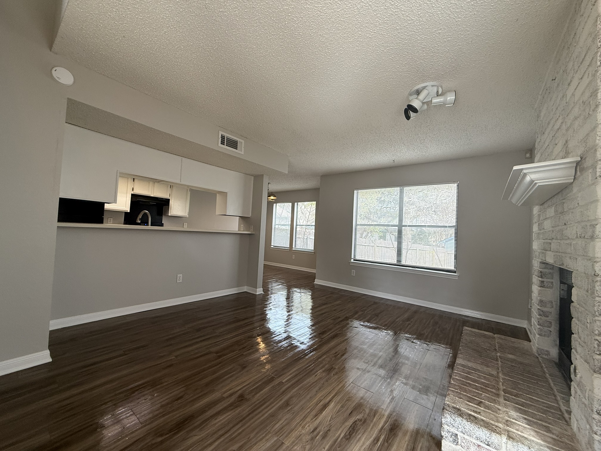 7806 Topawa Cove, Unit A Austin, TX 78729 - Photo 4 of 25 Unfurnished living room featuring a textured ceiling, a fireplace, and dark wood-style flooring