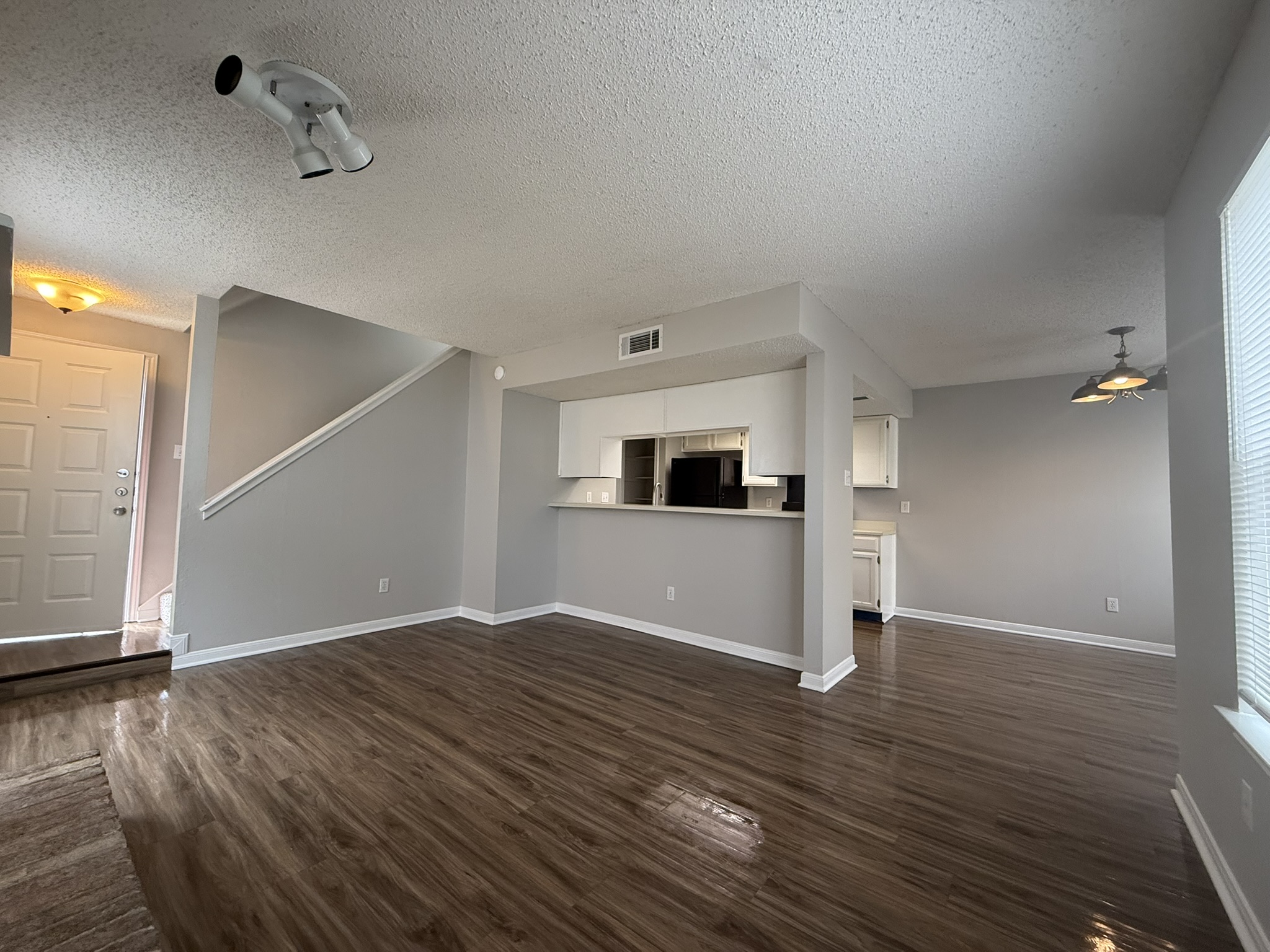 7806 Topawa Cove, Unit A Austin, TX 78729 - Photo 6 of 25 Unfurnished living room featuring a textured ceiling, dark wood finished floors, and a ceiling fan