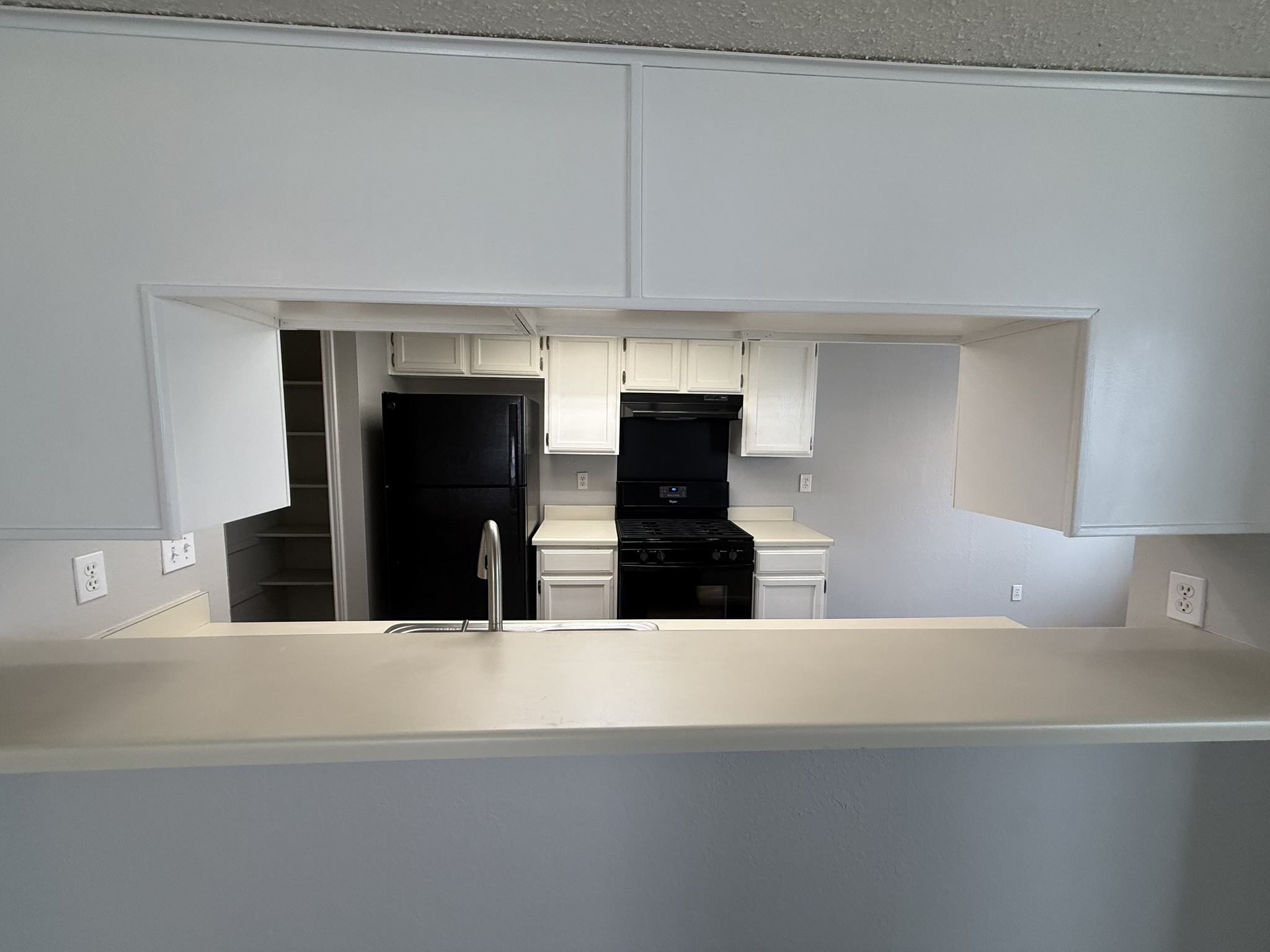 7806 Topawa Cove, Unit A Austin, TX 78729 - Photo 8 of 25 Kitchen with light countertops, black appliances, white cabinets, a peninsula, and under cabinet range hood