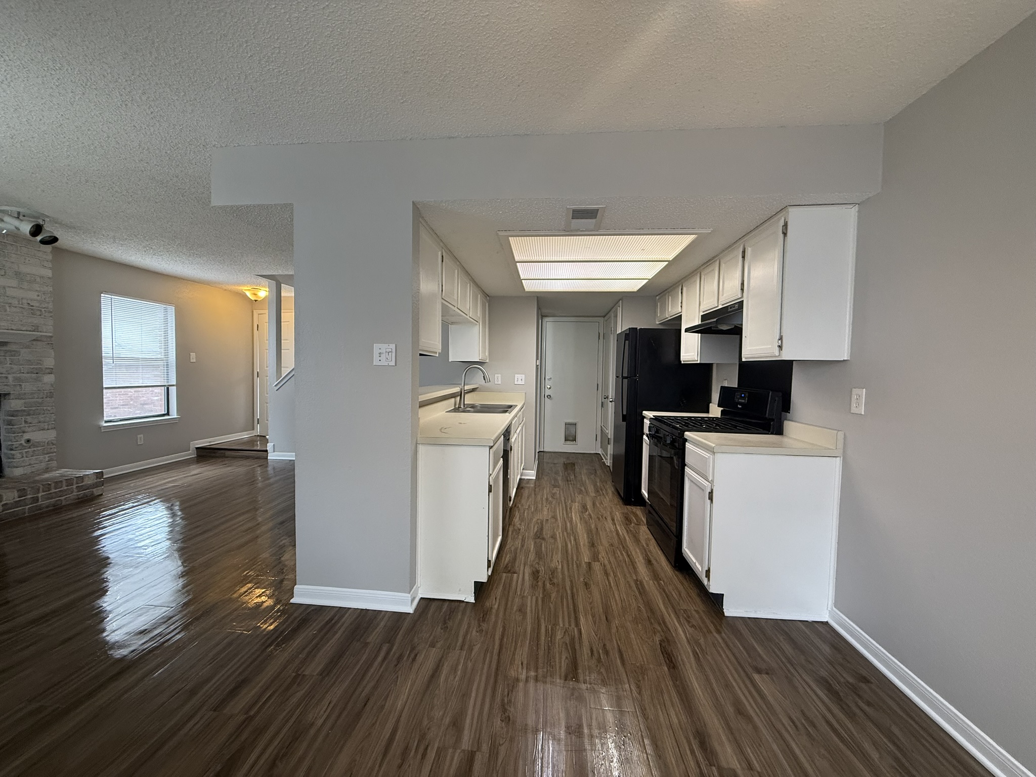 7806 Topawa Cove, Unit A Austin, TX 78729 - Photo 10 of 25 Kitchen featuring black gas range, light countertops, white cabinetry, a textured ceiling, and dark wood finished floors