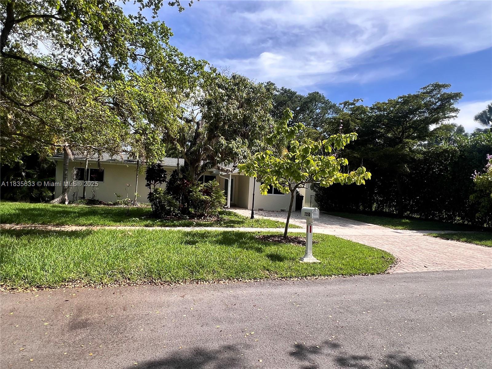 7350 Southwest 96th Street, Unit 7350 Pinecrest, FL 33156 - Photo 17 of 25 a front view of a house with a yard and a garage