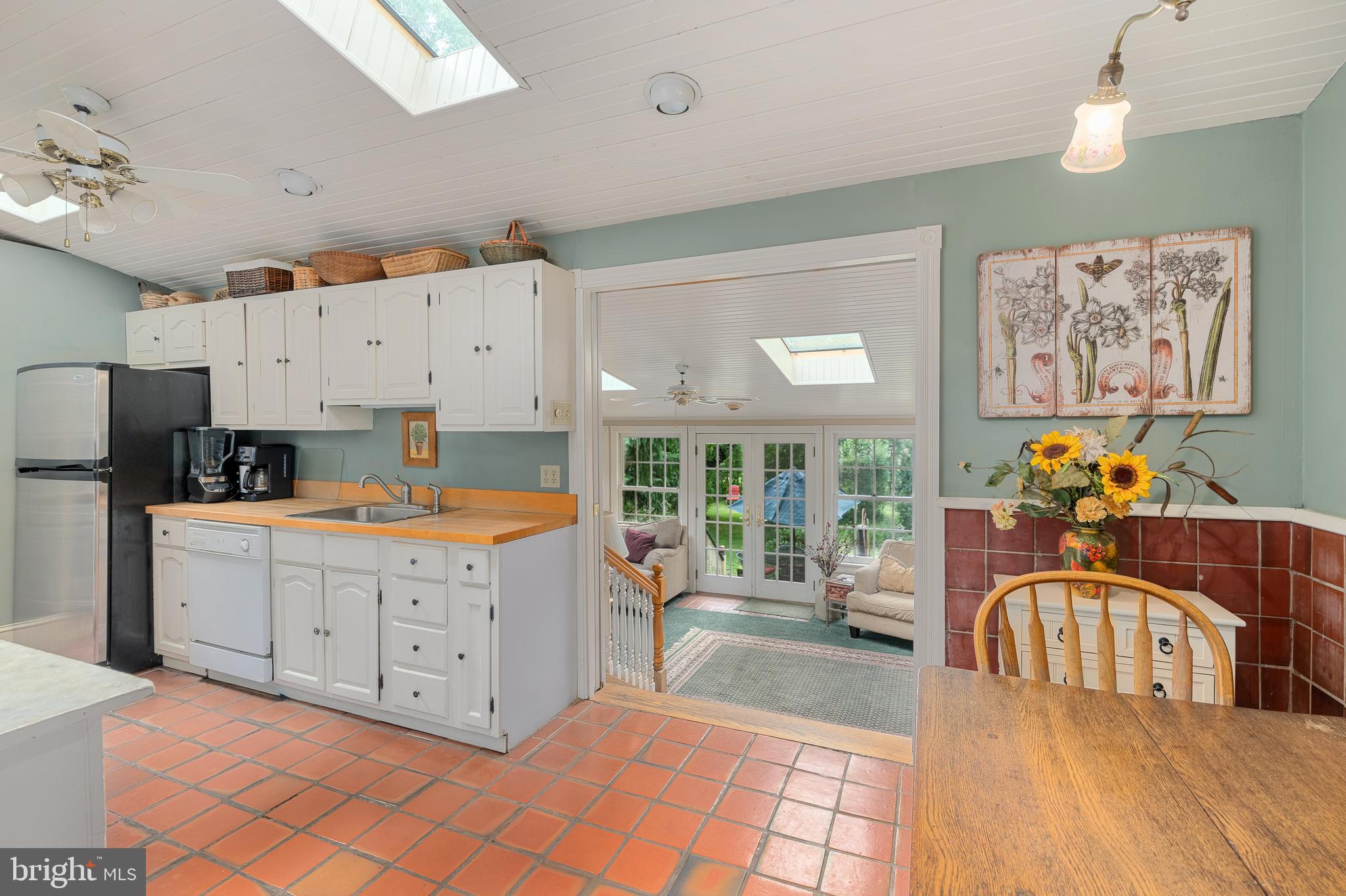 4140 Township Line Road Newtown, PA 18940 - Photo 27 of 41 a kitchen with stainless steel appliances granite countertop a stove a sink a refrigerator a microwave a dining table and chairs with wooden floor