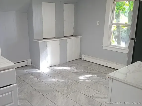 a view of a kitchen with white cabinets and a window