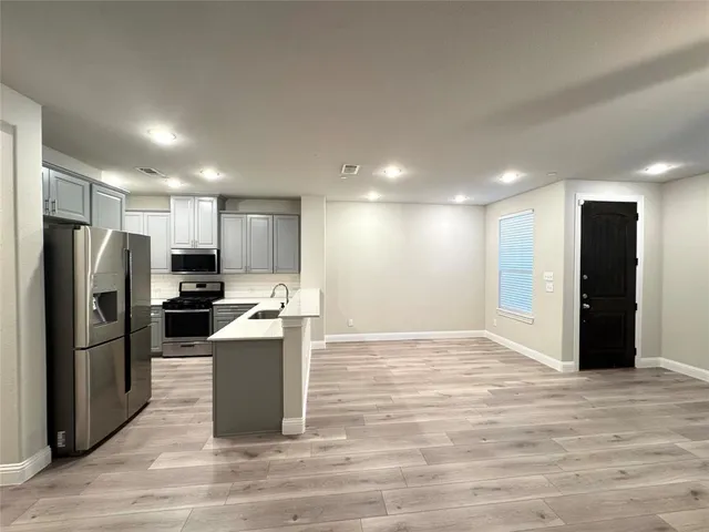 a view of a kitchen with kitchen island a sink wooden floor and a counter top space
