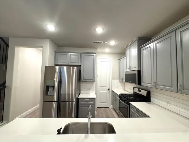 a view of a kitchen with a sink and refrigerator