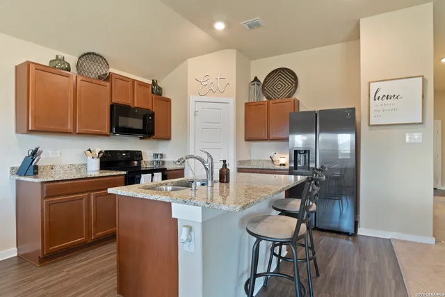 a kitchen with stainless steel appliances granite countertop a sink dishwasher a refrigerator cabinets and wooden floor