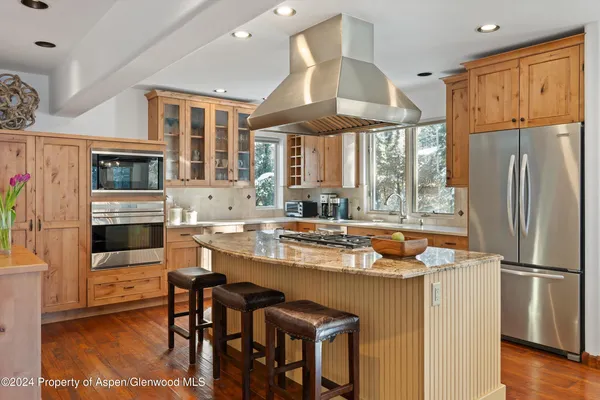 a kitchen with stainless steel appliances granite countertop a refrigerator a stove and a dining table with wooden floor