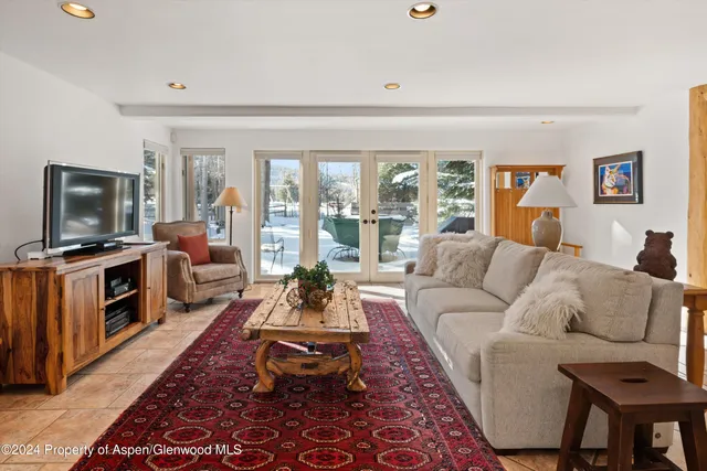 a living room with furniture a flat screen tv and a floor to ceiling window