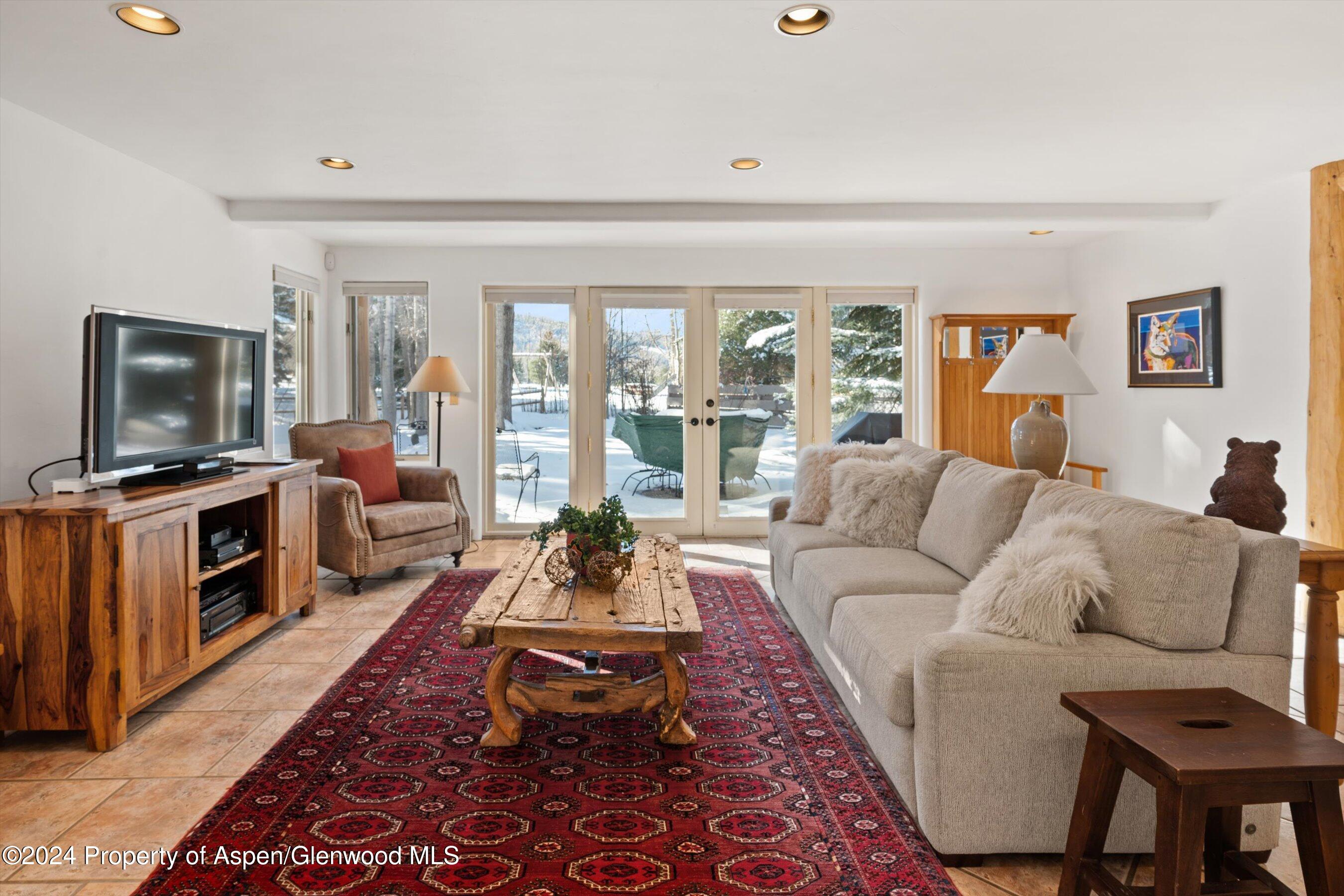 825 Cemetery Lane, Unit 2 Aspen, CO 81611 - Photo 32 of 47 a living room with furniture a flat screen tv and a floor to ceiling window
