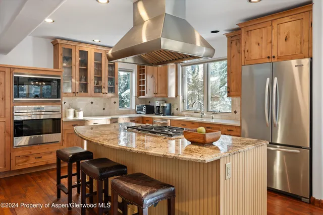 a kitchen with granite countertop a refrigerator and a stove top oven