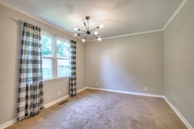 an empty room with windows and chandelier fan
