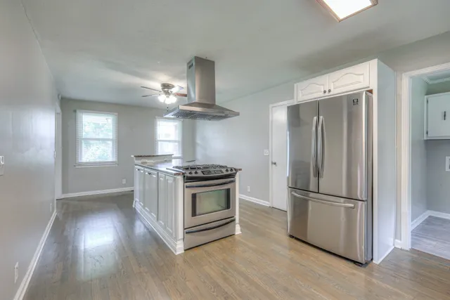 a kitchen with stainless steel appliances granite countertop a refrigerator a stove a microwave and a hard wood floor