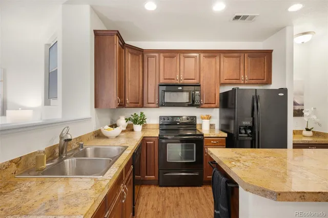 a kitchen with stainless steel appliances granite countertop a sink a stove and a refrigerator