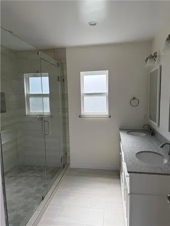 a bathroom with a granite countertop sink a mirror and shower