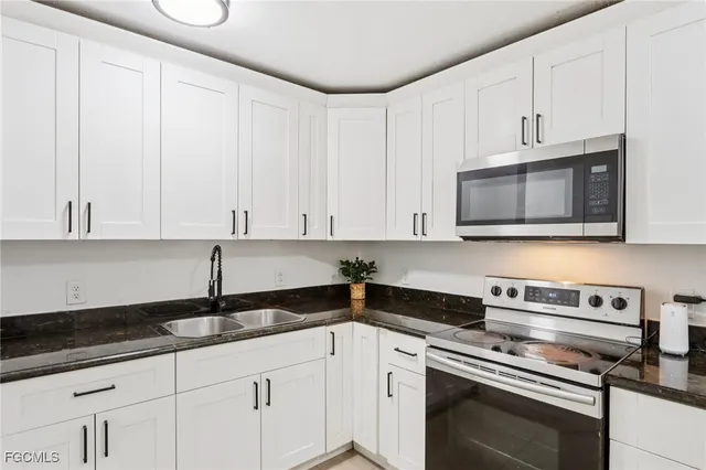 a kitchen with granite countertop white cabinets and stainless steel appliances