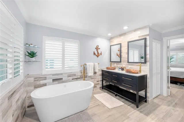 a spacious bathroom with a tub double vanity and window
