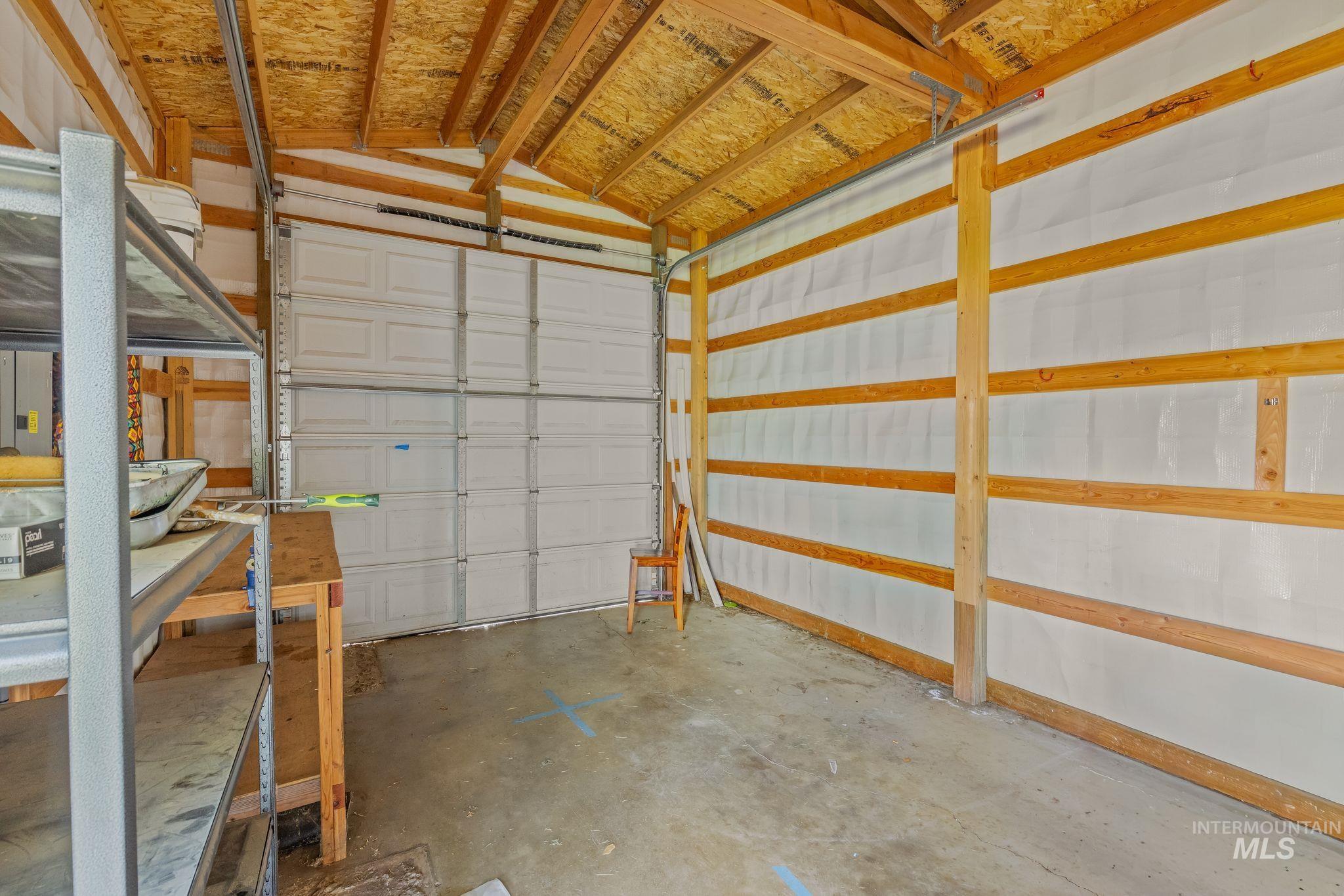 928 3rd Street Clarkston, WA 99403 - Photo 38 of 44 Interior garage space featuring a paneled overhead door, exposed wooden beam ceiling, concrete flooring, and insulated walls