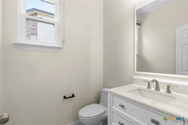 a bathroom with a granite countertop toilet sink vanity and mirror