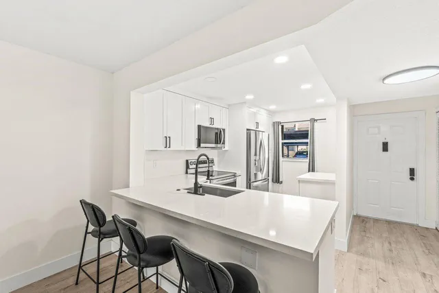 a kitchen with kitchen island a dining table chairs cabinets and stainless steel appliances