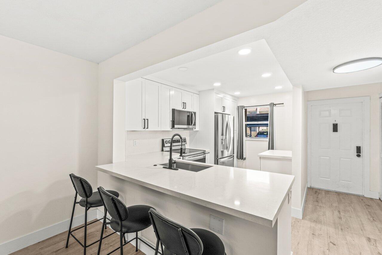 2935 Southwest 22nd Avenue, Unit 1060 Delray Beach, FL 33445 - Photo 2 of 21 a kitchen with kitchen island a dining table chairs cabinets and stainless steel appliances