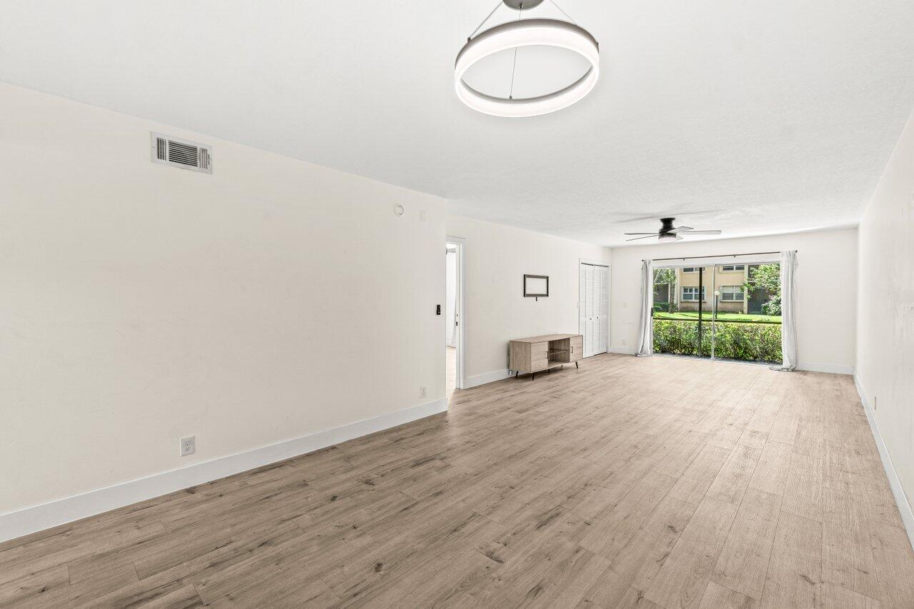 2935 Southwest 22nd Avenue, Unit 1060 Delray Beach, FL 33445 - Photo 8 of 21 a view of an empty room with wooden floor and a window