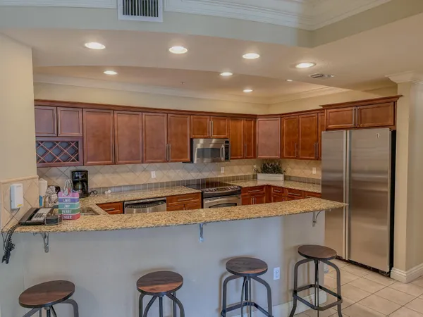 a kitchen with stainless steel appliances granite countertop a sink refrigerator and cabinets