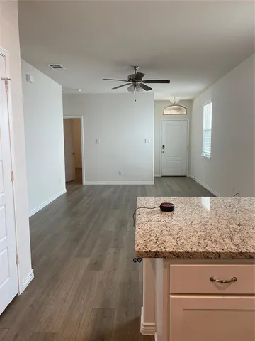 an empty room with wooden floor cabinet and windows