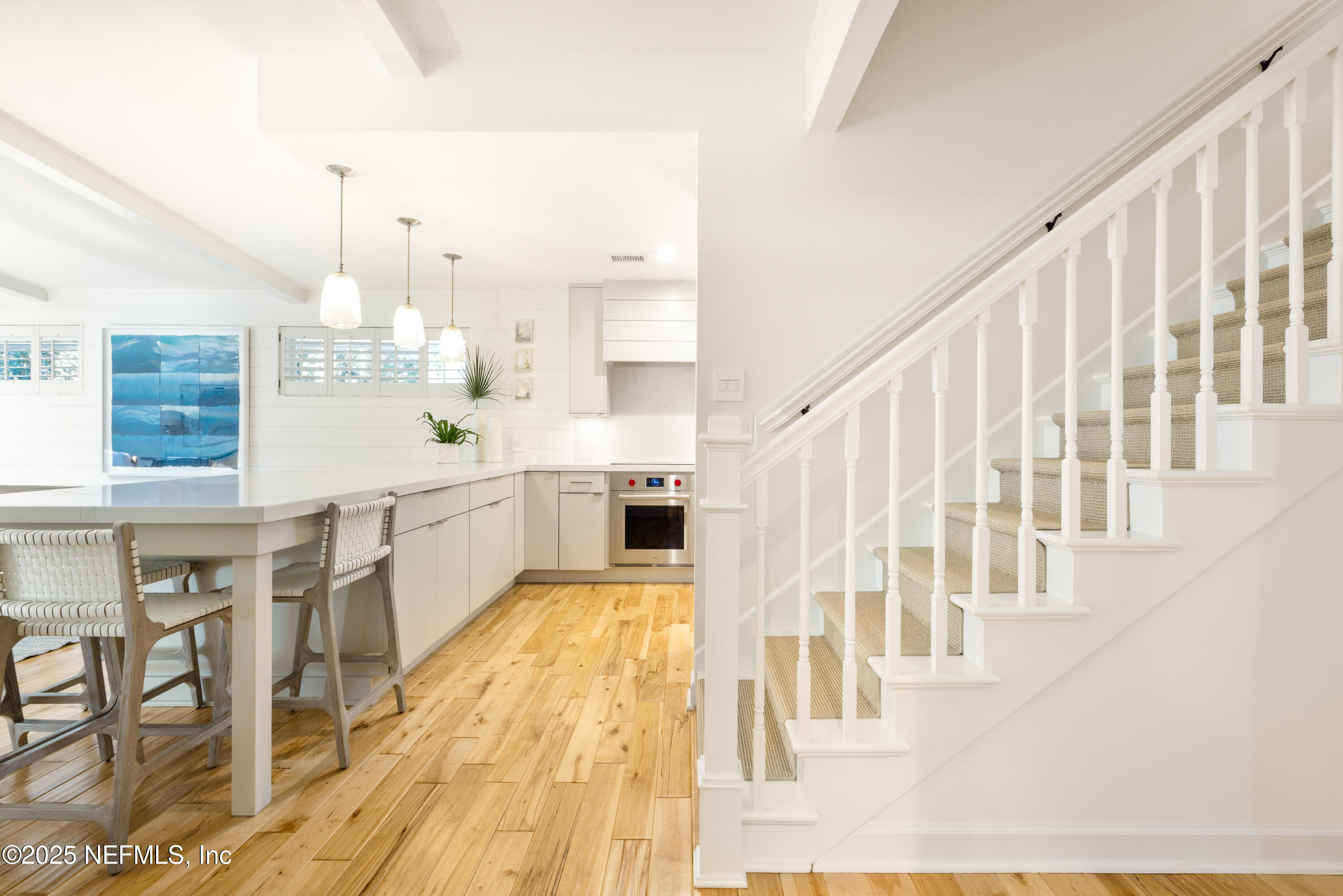 440 Ocean Boulevard Atlantic Beach, FL 32233 - Photo 8 of 34 a large white kitchen with wooden floor and stainless steel appliances