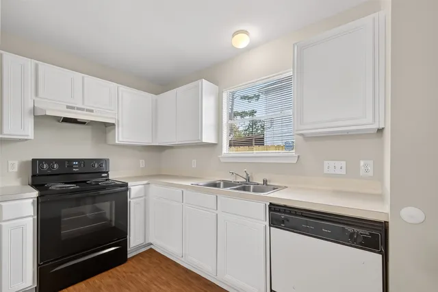 a kitchen with white cabinets and black appliances