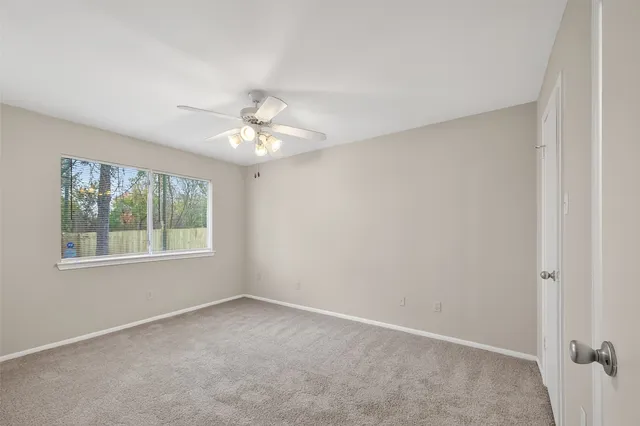an empty room with chandelier fan and windows