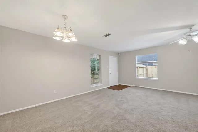 an empty room with windows and chandelier fan