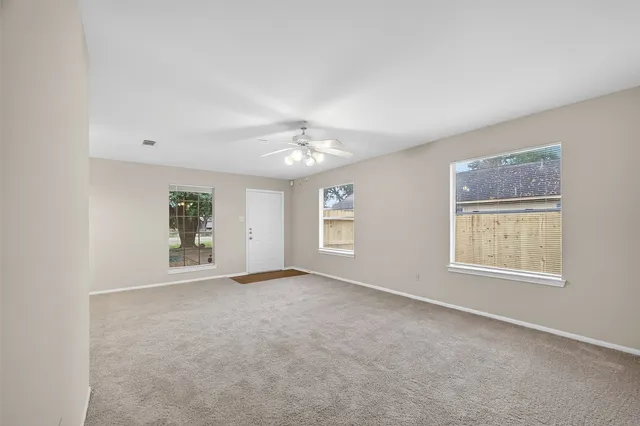 en empty room with windows and ceiling fan