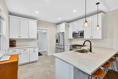 a kitchen with stainless steel appliances granite countertop a sink a stove a refrigerator cabinets and chairs