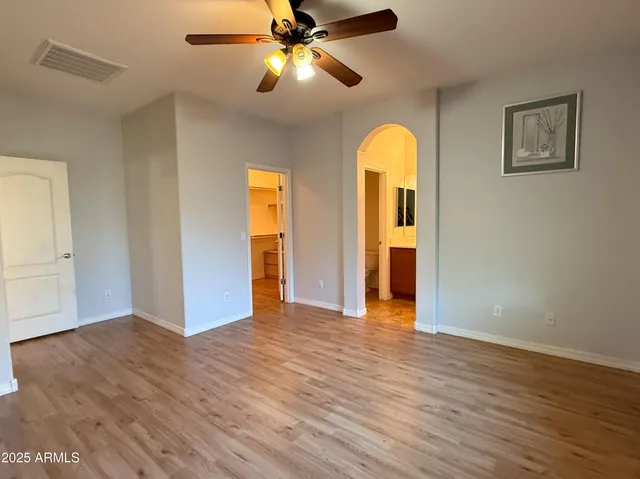 a view of empty room with wooden floor and ceiling fan