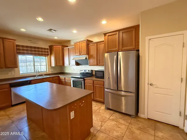 a kitchen with stainless steel appliances granite countertop a refrigerator a sink and a stove