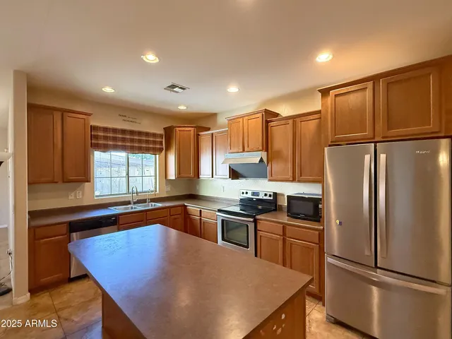 a kitchen with granite countertop a refrigerator stove top oven and sink
