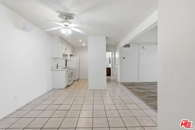 a view of an empty room and chandelier fan
