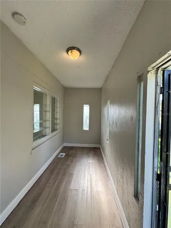 an empty room with wooden floor and windows