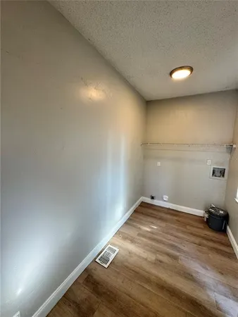 an empty room with wooden floor and fan