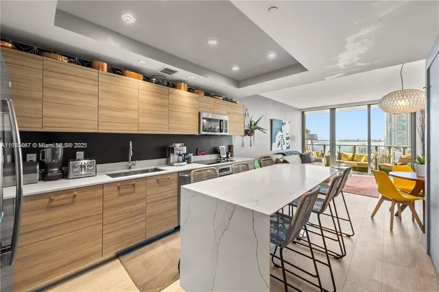 a kitchen with stainless steel appliances kitchen island granite countertop a table chairs sink and cabinets