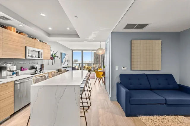 a living room with stainless steel appliances kitchen island granite countertop a couch and a view of living room