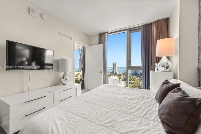 a bedroom with a bed television window and glass door