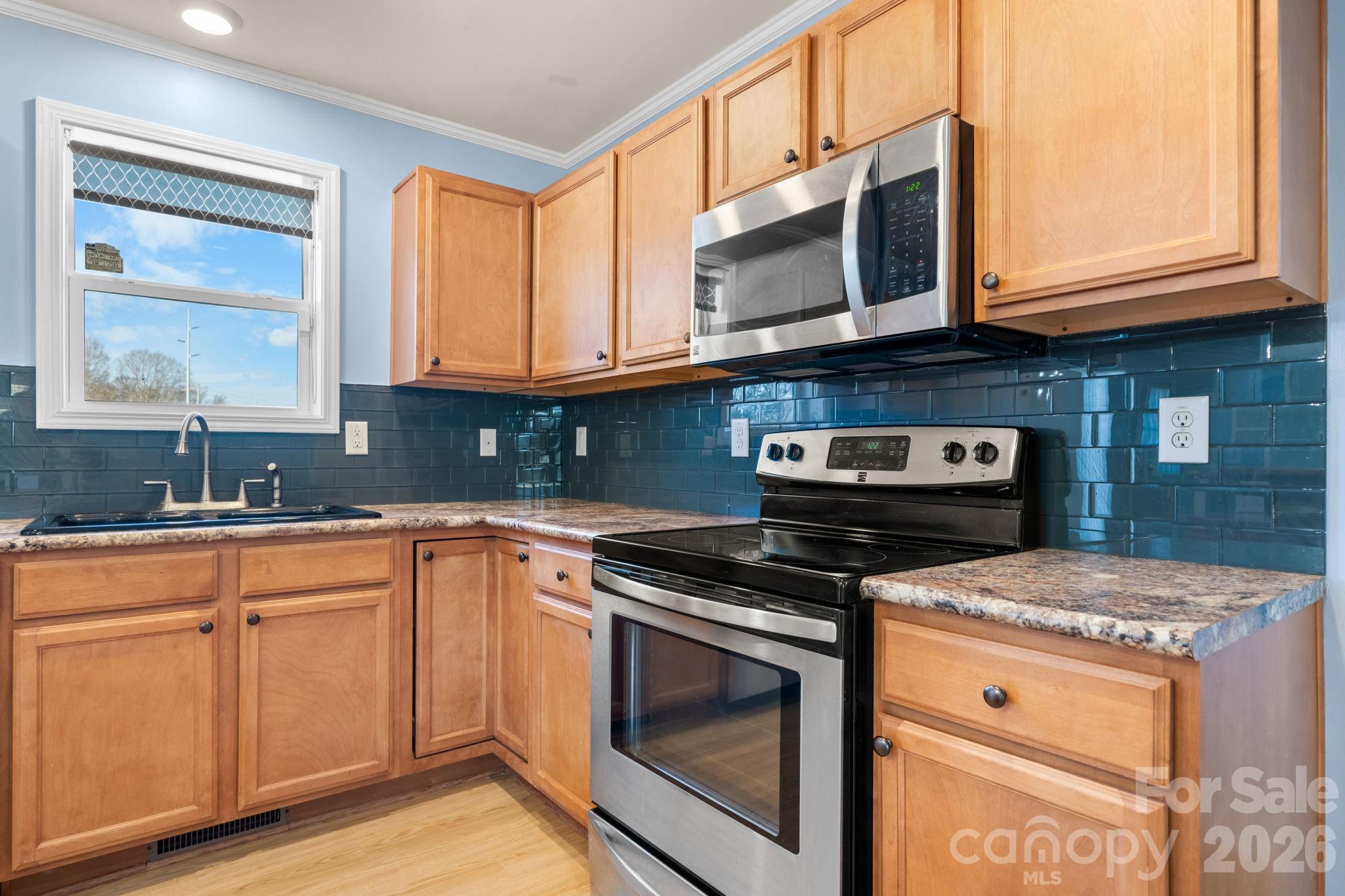 999 Stone Throw Drive Concord, NC 28025 - Photo 3 of 23 a kitchen with granite countertop a stove microwave and sink